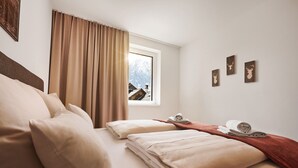 A hotel room with a bed, a window with curtains, and a view of mountains. - Alm Lodge A2 - Tauplitz Lodges (Tauplitz)