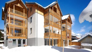 A multi-story wooden chalet with balconies, surrounded by snow. - Alm Lodge A3 - Tauplitz Lodges (Tauplitz)
