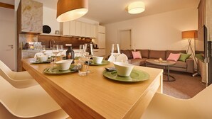 A modern living room with a wooden dining table set for four, a sofa, and a coffee table. - Alm Lodge A3 - Tauplitz Lodges (Tauplitz)