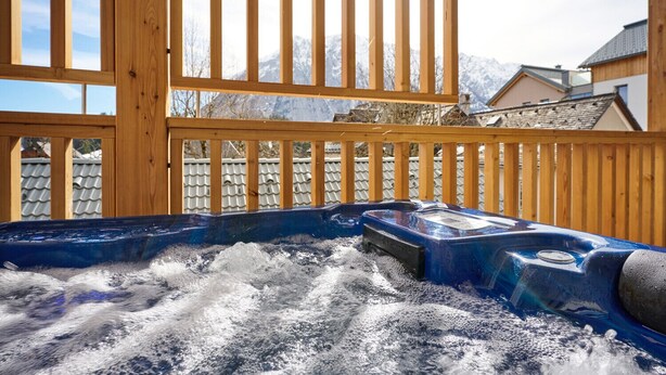 A hot tub with a wooden deck and a view of snow-covered mountains. - Alm Lodge A3 - Tauplitz Lodges (Tauplitz)