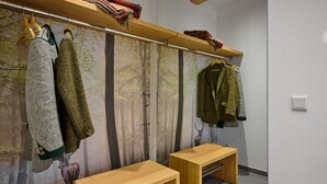 A room with a wooden bench, a coat rack with jackets, and a forest-themed wall mural. - Alm Lodge A3 - Tauplitz Lodges (Tauplitz)