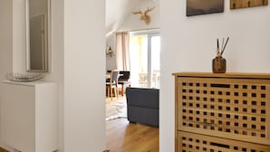 Un salon moderne avec un canapé gris, un plancher en bois et un coin repas à l’arrière-plan.