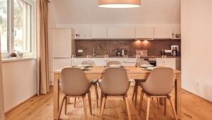 A modern kitchen with a dining table set for four, equipped with wine glasses and plates. - Alm Lodge A13 - Tauplitz Lodges (Tauplitz)