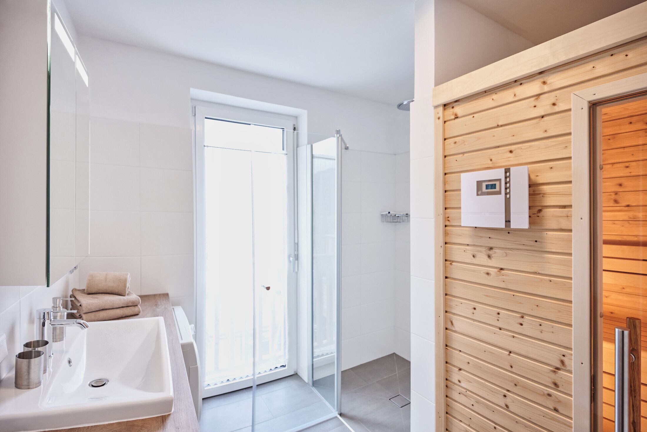 Een moderne badkamer met een ruime wastafel, een douchecabine van glas en een houten wandpaneel.
