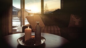 A cozy room with a large window, a candle, a bottle, and a deer pillow. - Wasserfall Lodge C1 - Tauplitz Lodges (Tauplitz)