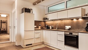 Eine moderne Küche mit weißen Schränken, einem Backofen, einer Mikrowelle und einer Kaffeemaschine.