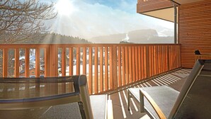 Un balcon offrant une vue sur les montagnes et un ciel ensoleillé.