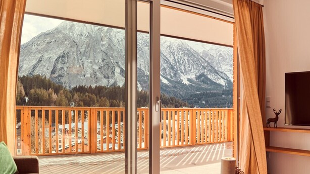 Habitació amb una gran porta corredissa de vidre que dona a un balcó amb vista a la muntanya.