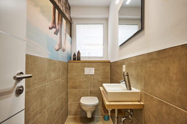 Une petite salle de bain comprenant des toilettes, un lavabo et un miroir au-dessus du lavabo.