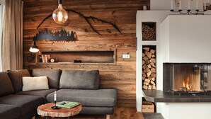 Un salon moderne avec un mur en bois, une cheminée, un canapé et une petite table d’appoint ronde en bois.