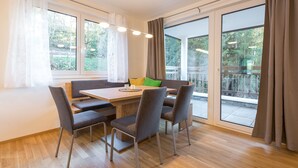 Un comedor con una mesa de madera, sillas tapizadas en gris y vistas a un balcón con barandilla.
