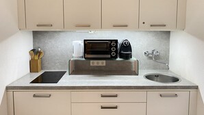 Een moderne keuken met een ingebouwde oven, koffiezetapparaat en een spoelbak.