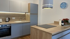 Ett modernt kök med en inbyggd ugn, en kaffemaskin och en vattenkokare på bänkskivan.