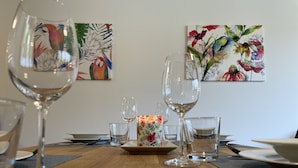Ett matbord med vackert glas, ett ljus som mittpunkt och blommotiv på väggarna.