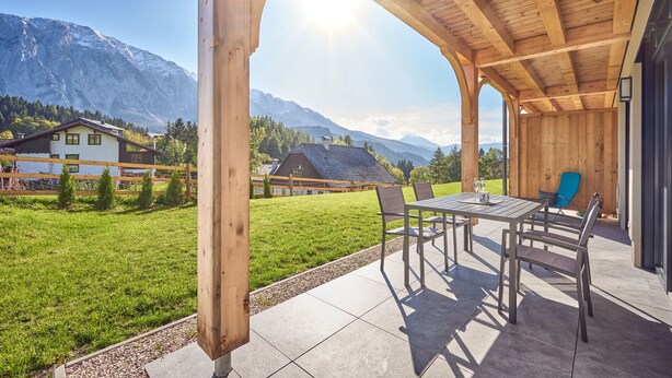 A covered outdoor area with a table and chairs, overlooking a mountainous landscape. - Panorama Lodge Alpine Living 201 (Tauplitz)