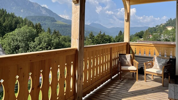Une terrasse en bois offrant une vue sur les montagnes et les arbres.