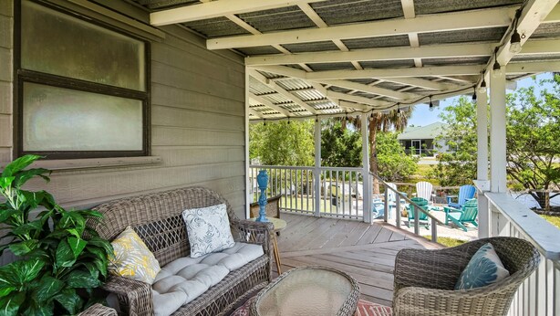 A covered porch with wicker furniture, a glass table, and a potted plant. - Come Stay In This Charming & Cozy Home In The Heart Of Naples (Naples)