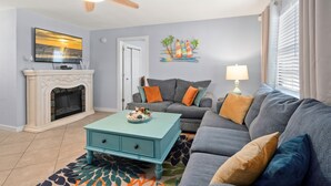 A living room with a fireplace, a sofa, a coffee table, and a ceiling fan. - Come Stay In This Charming & Cozy Home In The Heart Of Naples (Naples)