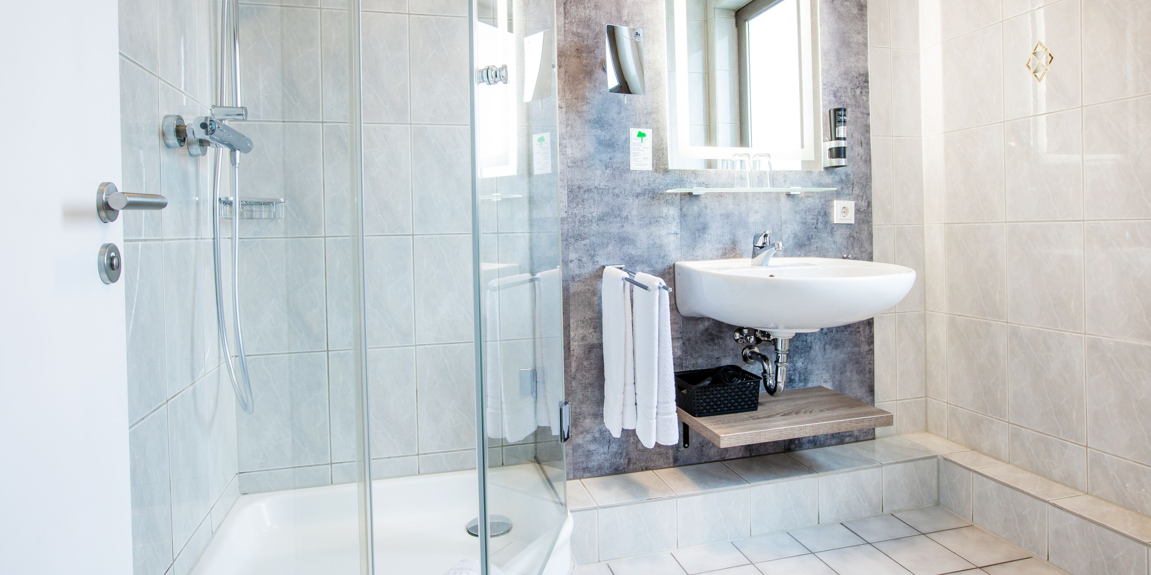 Ein modernes Badezimmer mit einer gläsernen Dusche, einem weißen Waschbecken und einer Marmor-Spritzschutzwand.