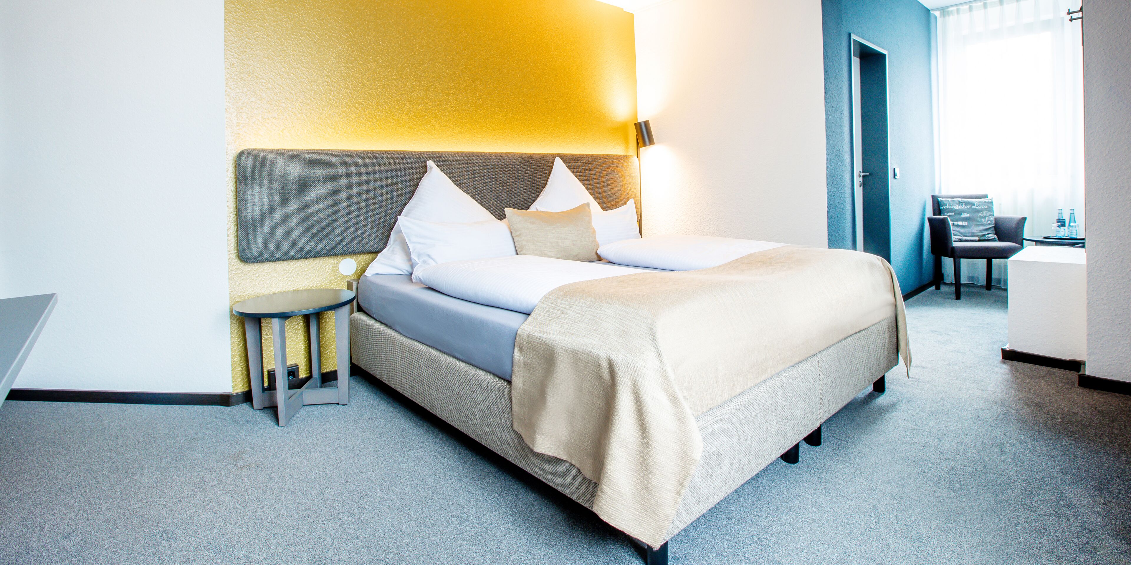 Una habitación de hotel moderna con una cama, mesita de noche y una lámpara.