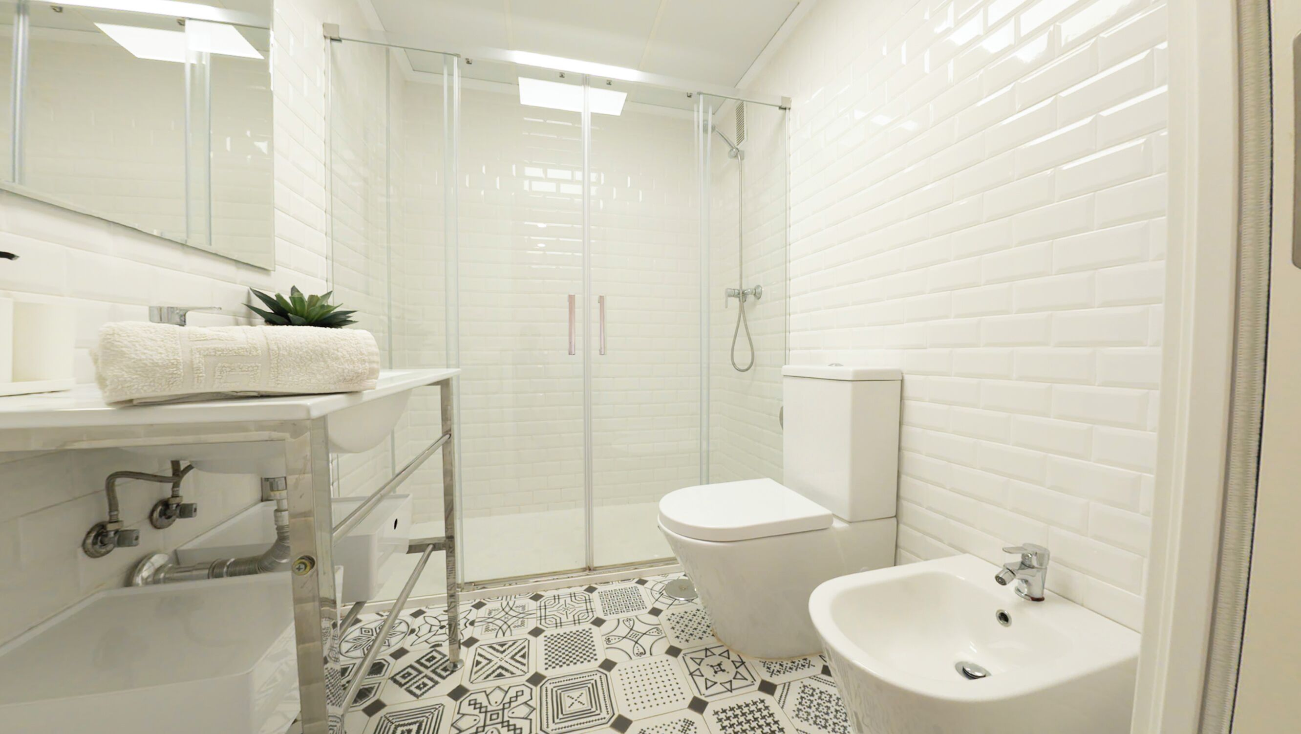 A modern bathroom with a shower, toilet, sink, and a patterned floor.