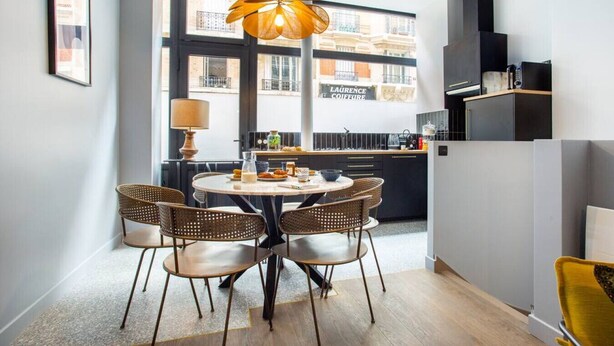 A modern kitchen with a round dining table, wicker chairs, and a pendant light. - Appart indépendant, 2chambres!Parc des expositions (Paris)