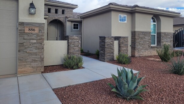 A residential building with a stone facade, a number '886' sign, and a well-maintained garden with agave plants. - CASITA NEAR ZION (Hurricane)