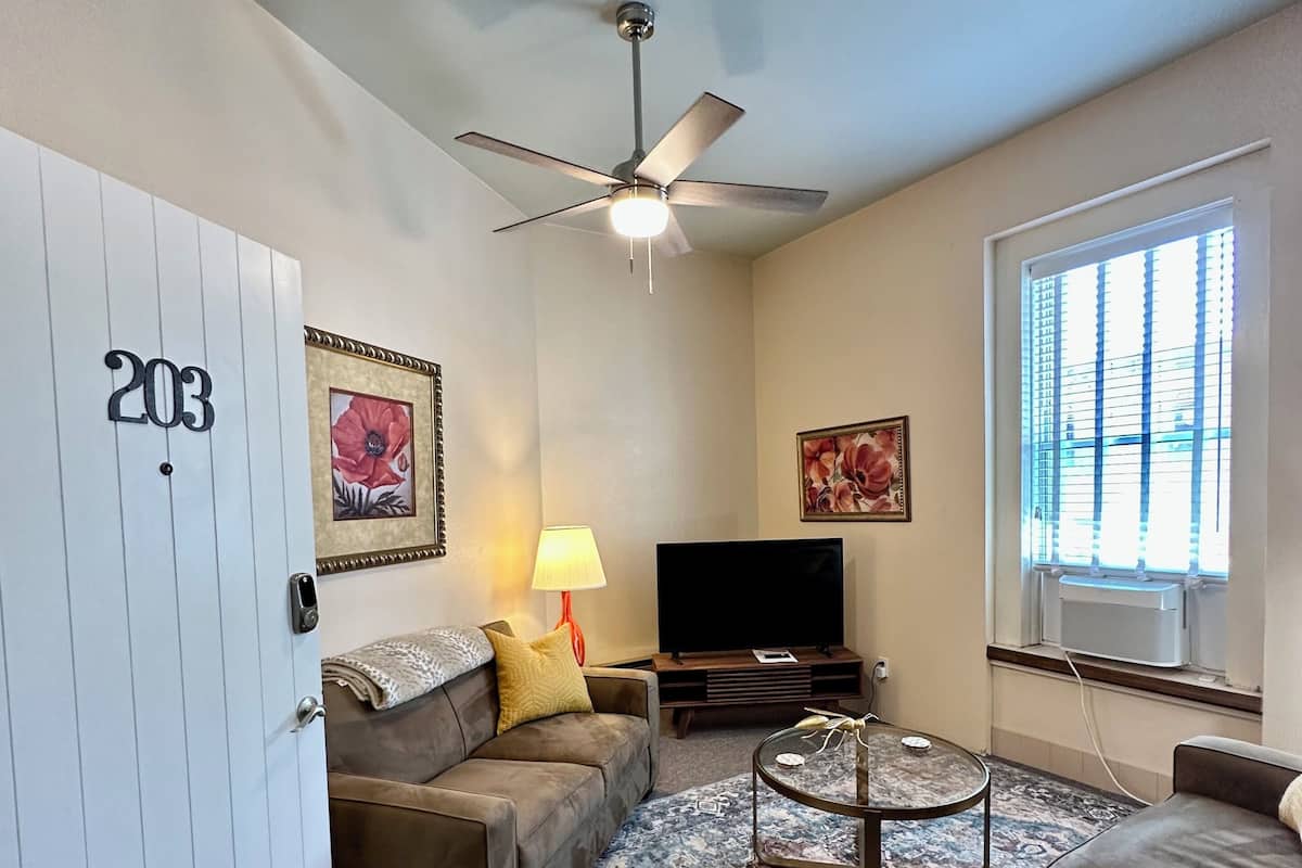 A living room with a sofa, a coffee table, a TV, and a ceiling fan.