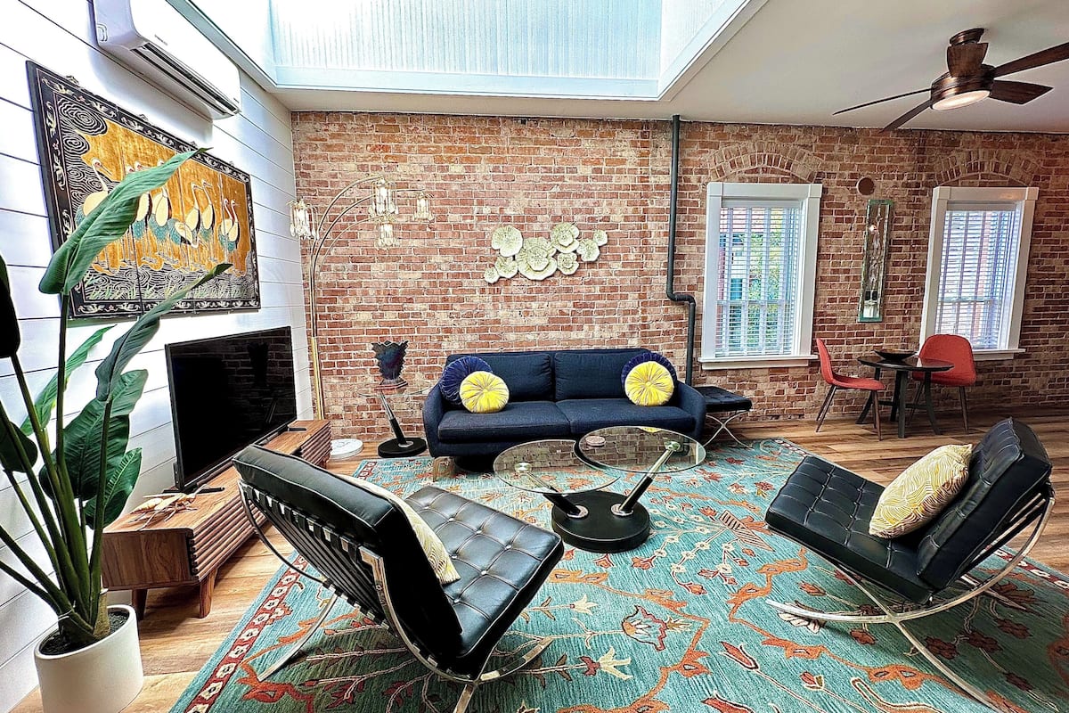 A modern living room with a brick wall, a blue sofa, a coffee table, and a ceiling fan.