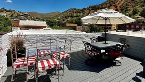 Een terras op het dak met zitplaatsen buiten, een tafel en een parasol.