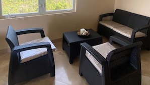 A room with a large window, wicker furniture, and a ceiling fan. - The Four Breezes With Pool and View (providenciales)