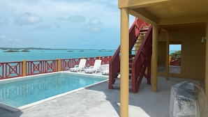 A pool area with a view of the ocean and islands, a staircase, and a covered seating area. - The Four Breezes With Pool and View (providenciales)
