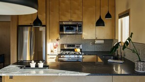 Una cocina moderna con electrodomésticos de acero inoxidable, armarios de madera e iluminación colgante.