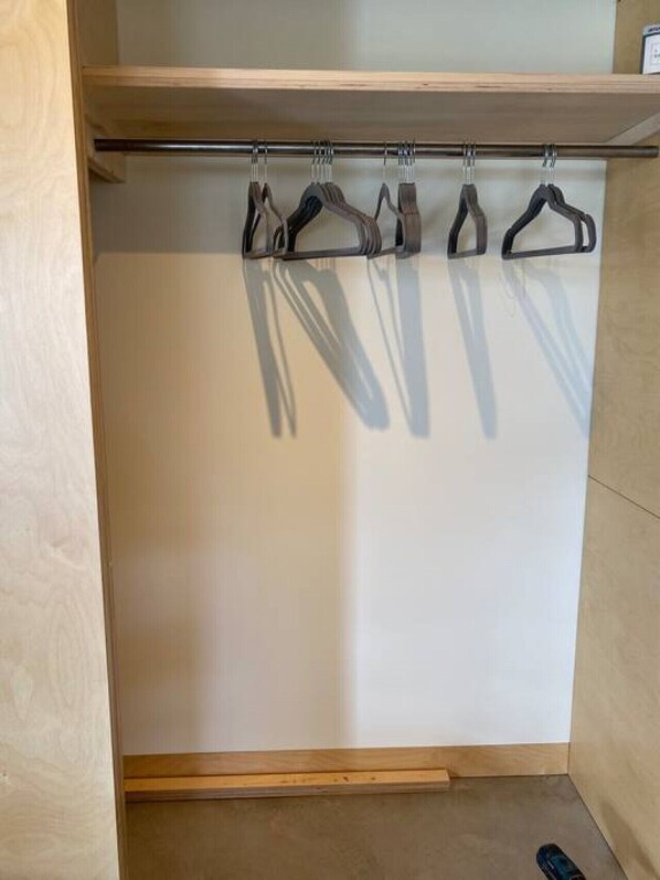 A wooden closet with a metal rod holding several black hangers.