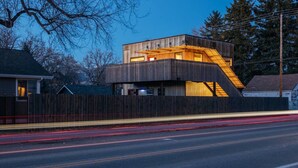 Un edificio moderno con un diseño arquitectónico único, que presenta fachada de madera y una escalera destacada.