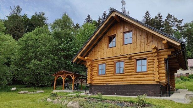 A log cabin with a covered patio and a small garden area.