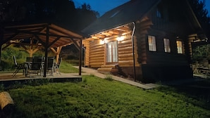 A log cabin with a covered patio, outdoor seating, and a chimney.
