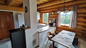 A cozy cabin-style kitchen with a refrigerator, sink, and dining area with chairs and a table.