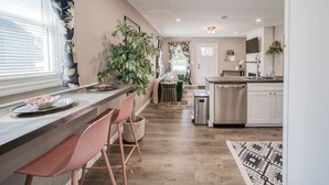 Una cucina moderna con un piano di lavoro in legno, elettrodomestici in acciaio inossidabile e un'area pranzo con sedie rosa.