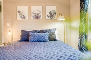 Une chambre à coucher avec un lit, des oreillers, une lampe de chevet et des œuvres d’art murales.