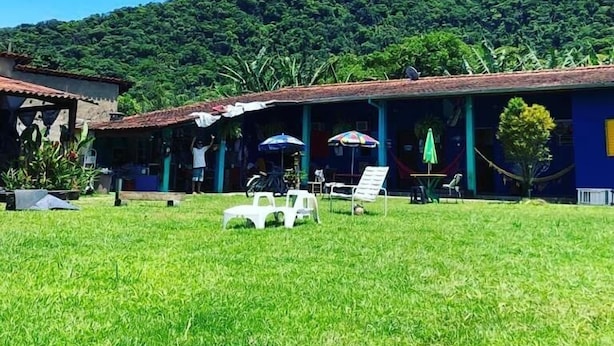 Un hotel con un espacio exterior techado, sillones blancos y sombrillas.