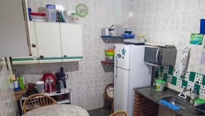 Una cocina compacta con una mesa redonda, sillas de mimbre, un refrigerador, un microondas y un lavabo.
