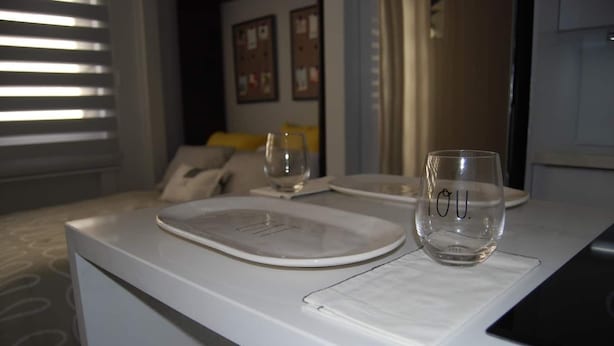 Un espace de restauration propre et moderne, avec une table blanche dressée pour deux personnes, agrémentée d’une assiette et d’un verre.