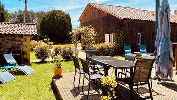 Une terrasse en bois avec des meubles d’extérieur, une table et des chaises.