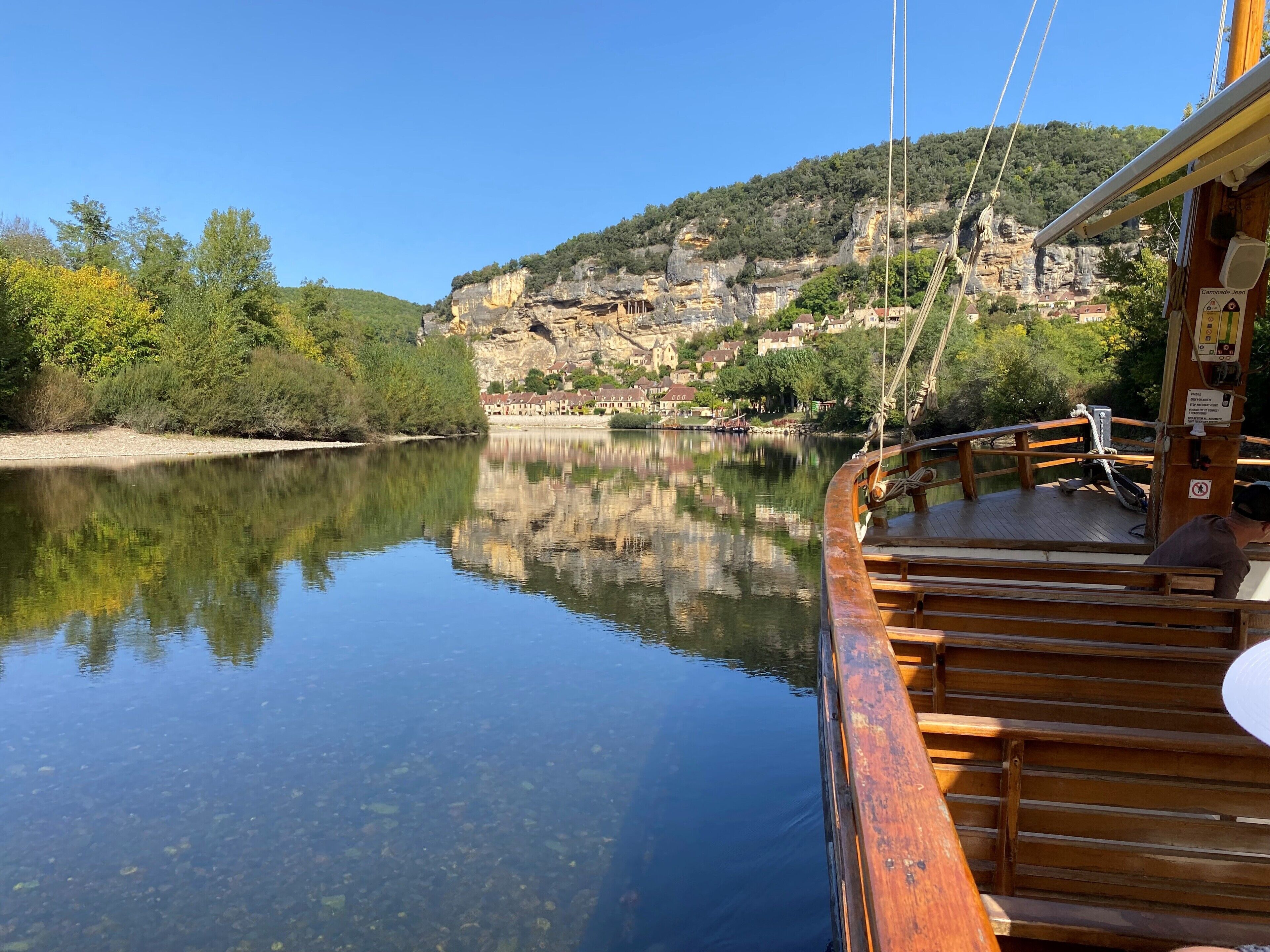 Un bateau en bois offrant une vue dégagée sur une rivière paisible, dont les eaux reflètent le paysage environnant.