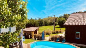 A swimming pool with a wooden deck, a barbecue grill, and a small shed.