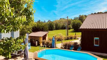 Une piscine avec une terrasse en bois, un barbecue et un petit abri de jardin.