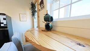 Una mesa de comedor de madera con una silla, un refrigerador, un ventanal y un cartel en la pared.
