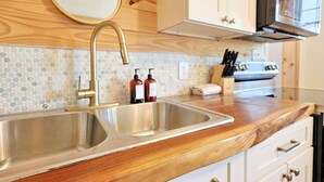 Een keuken met een houten aanrecht, een roestvrijstalen spoelbak en een magnetron.