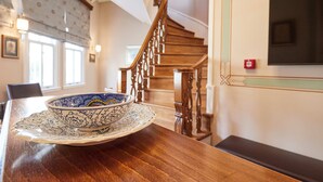 A dining area with a wooden table, a decorative bowl, a staircase, and a wall-mounted television. - White Palace Old City Boutique Hotel (Istanbul)